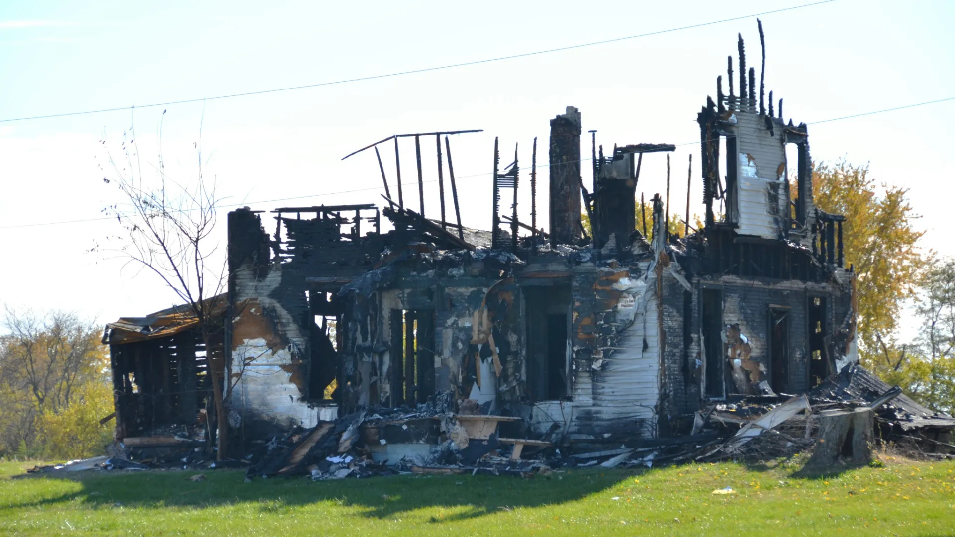 A severely fire-damaged and charred two-story home standing in a field, representing the catastrophic property losses handled by Evolve Claims public adjusters.